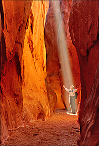 Man lighted by sunbeam at the bottom of a 
rock crevasse by Don Paulson