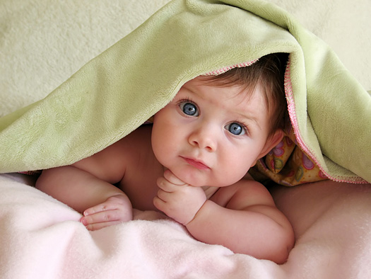 baby looking out from under blanket