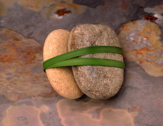 Stones wrapped in grass blades on a stone background.